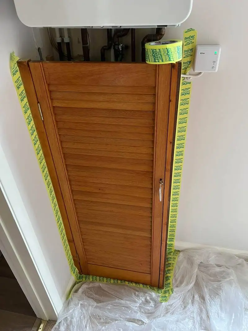 Orange pine louvred cupboard door masked with tape before repainting
