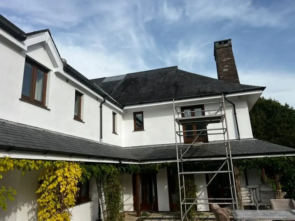 The house after a full exterior repaint, walls bright white, with the scaffold tower still up