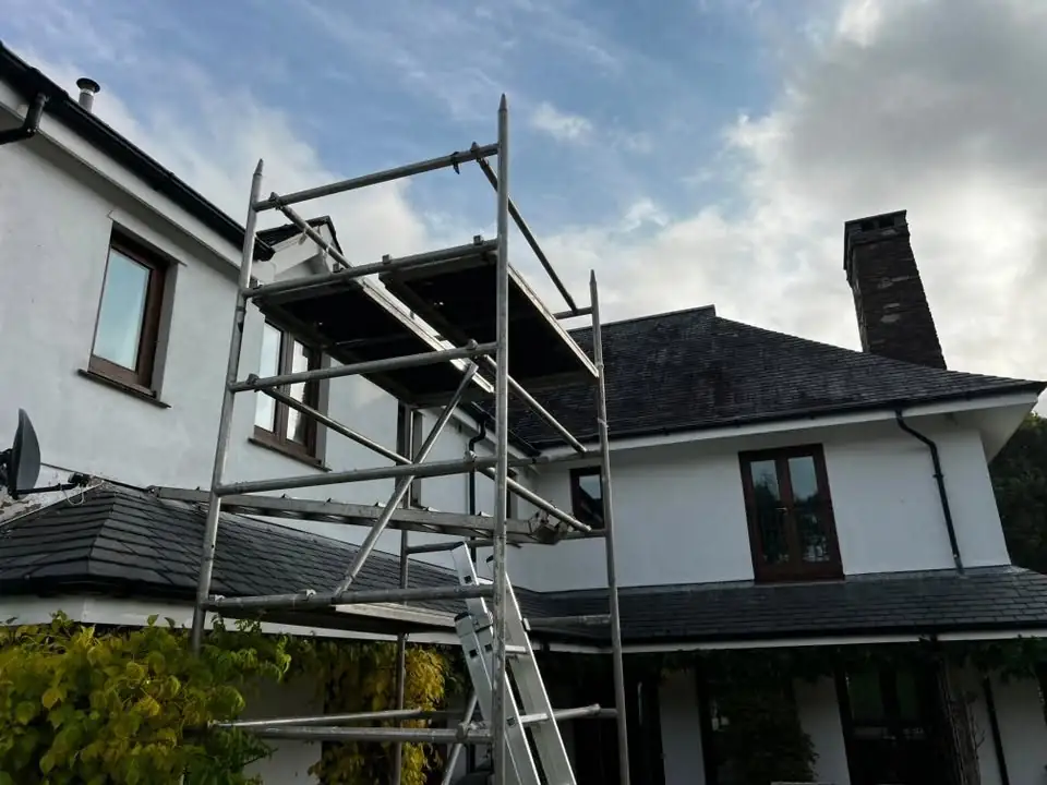 Scaffold tower set up against a rendered house before its exterior repaint