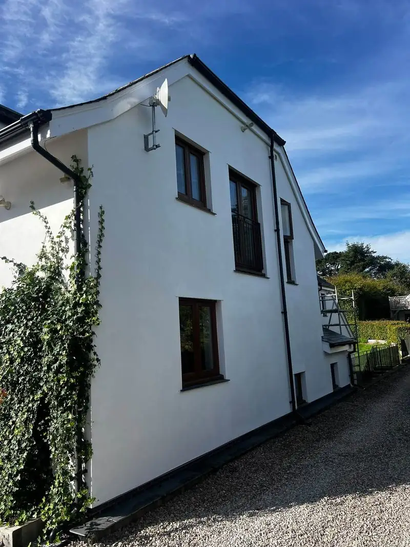 Side of the house after the exterior repaint, with bright white walls and dark window frames
