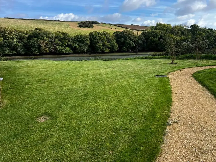 Freshly mown, striped lawn and gravel path overlooking the estuary