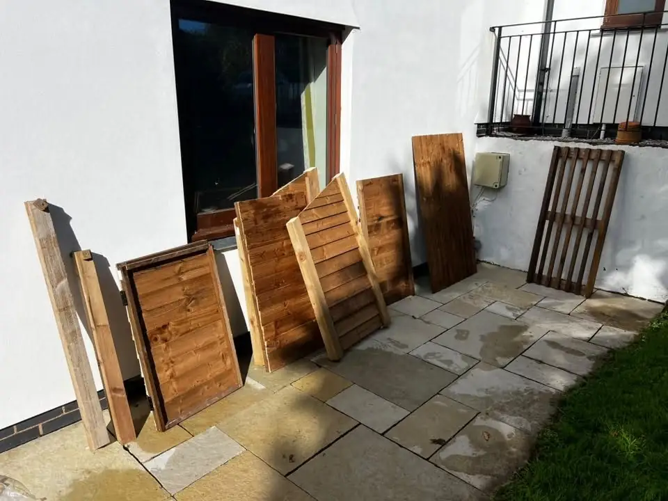 Timber panels for a log store laid out against a wall before assembly