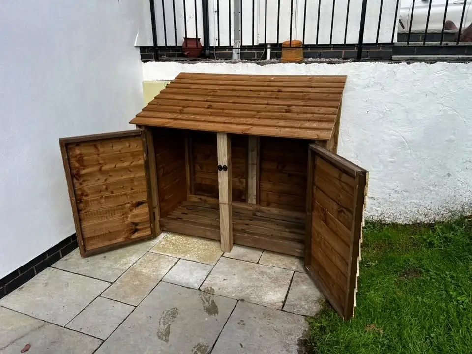 Timber log store assembled on the patio with its doors open, before any logs go in