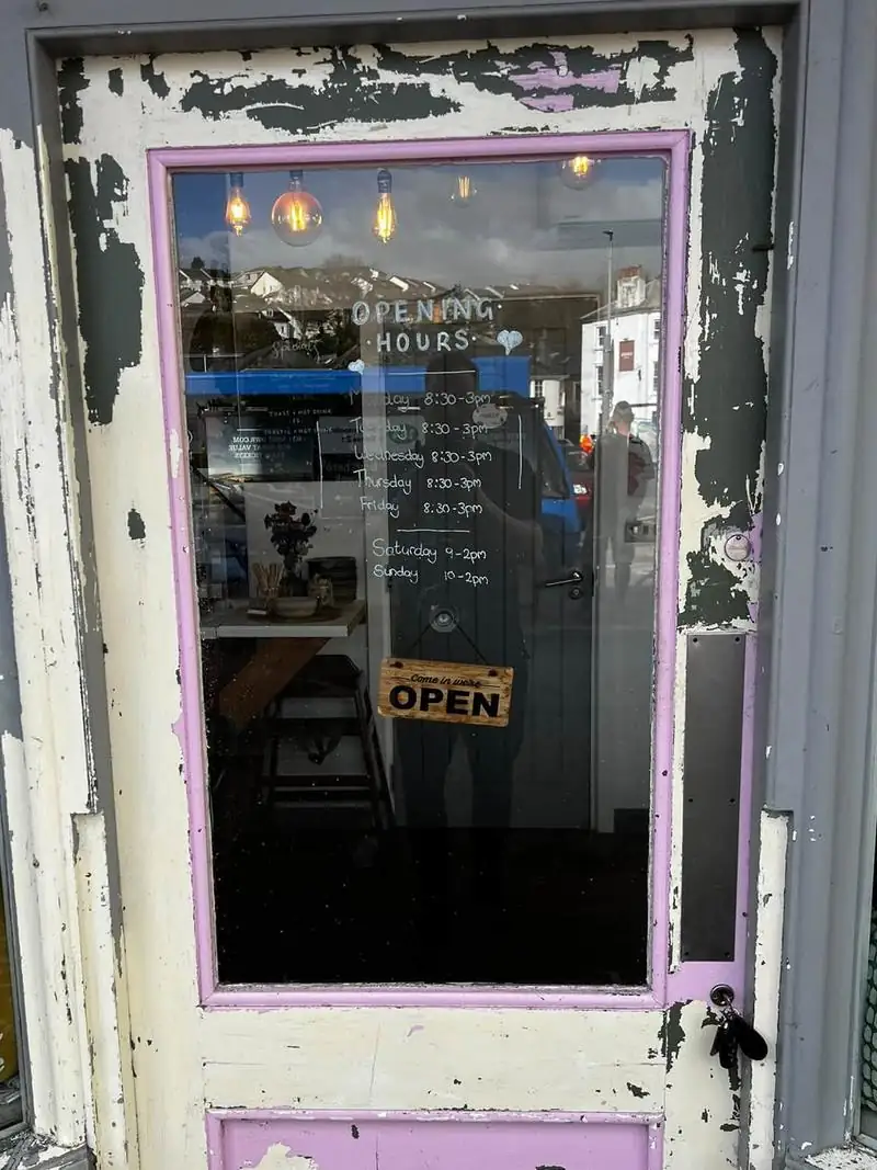 Shop door before repainting, with the paint peeling back to bare wood